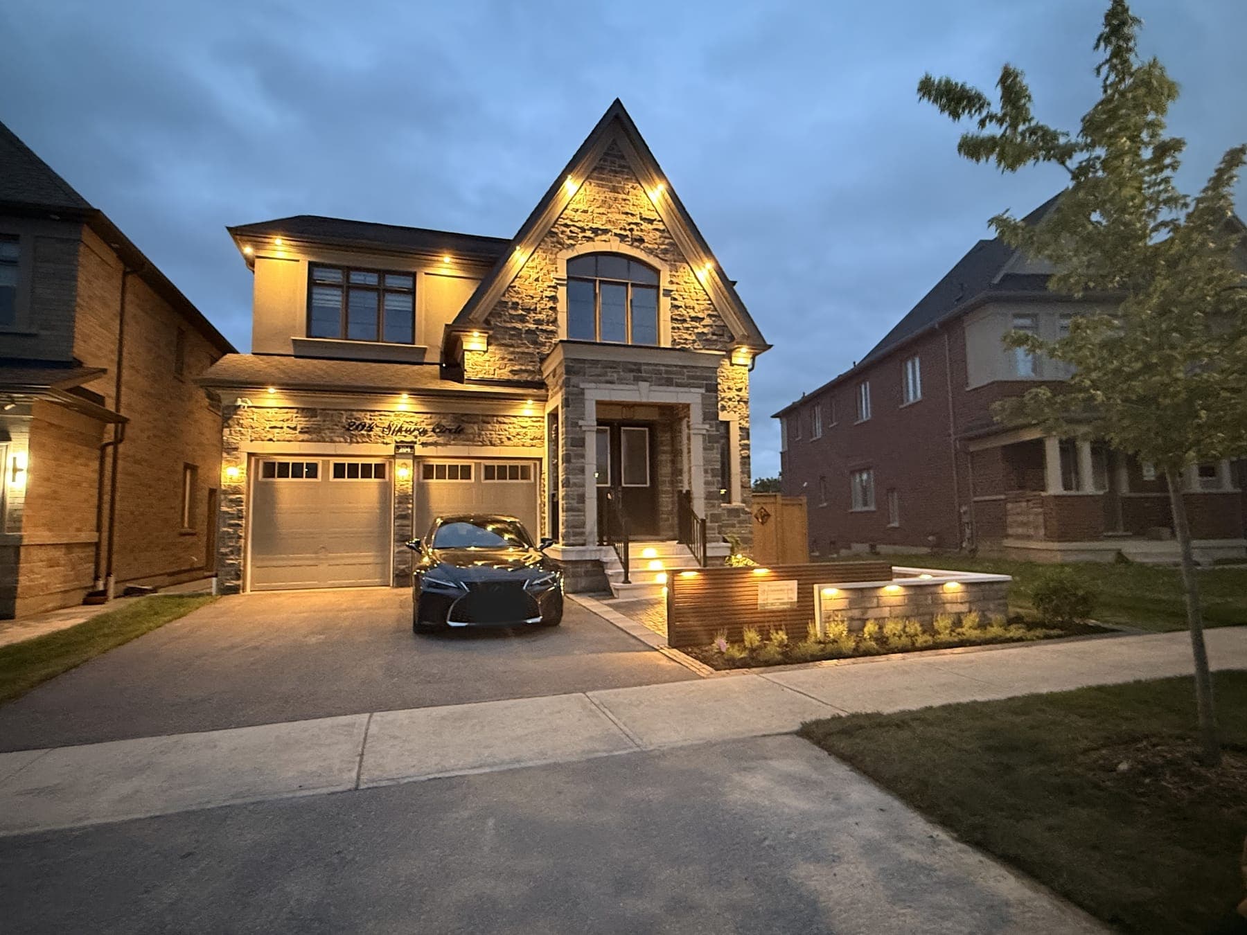 Interlock walkway and driveway with a raised paver planter wall and inset lighting at dusk